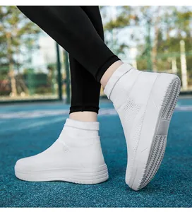 Detailansicht weißer atmungsaktiver Fly-Knit-Sneaker mit dicken Sohlen auf einem Sportplatz