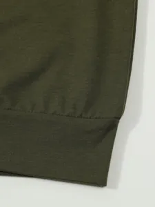 Close-up of olive green knit fabric and ribbed hem detail on a men's polo shirt