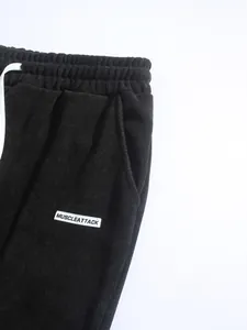 Gros plan sur la texture velours côtelé noir et l'étiquette sur le pantalon homme