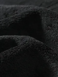 Macro detail showing the soft, textured black coral velvet fabric of the sweatshirt.