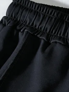 Detailed macro view of elastic waistband and black twill fabric on men's cargo pants.