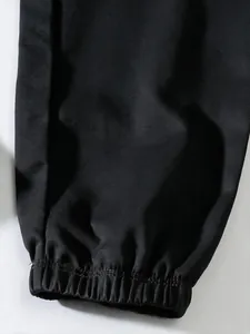 Close-up detail of black men's cargo pants showing elasticated cuff and twill fabric texture