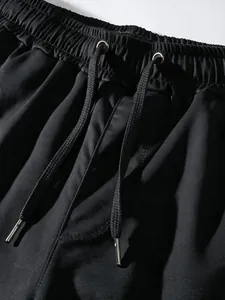 Close-up of black cargo pants elastic waistband with drawstring and metal tips