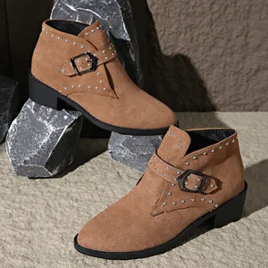 Detalle de botines de ante marrón con remaches plateados y hebillas metálicas laterales