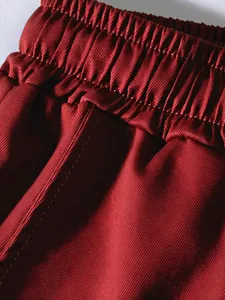 Close-up of elastic waistband on deep red men's solid color cargo joggers