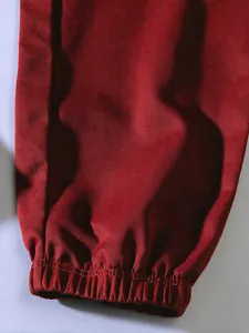 Detailed view of red cargo pants showing twill fabric texture and elasticated cuff.