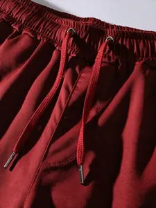 Detailed view of burgundy cargo pants waistband with elastic band and metal-tipped drawstring