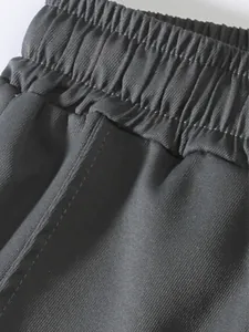 Close-up detail of the elastic waistband on men's casual solid color cargo pants.