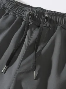 Close-up of elastic waistband and metal-tipped drawstring on dark grey cargo pants