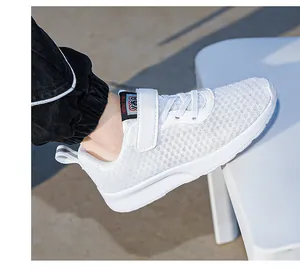 Close-up of white breathable mesh kids sneakers featuring a velcro strap and soft sole design