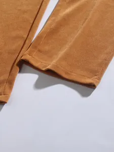 Close-up of brown corduroy trousers showing the high-quality fabric texture and hem detail.