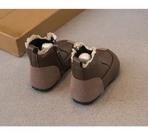 Detailed view of brown leather girls' boots with lace trim and side zipper closure