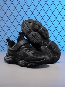 Detailed view of all-black children's running shoes with breathable mesh and chunky sole.
