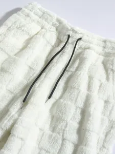Close-up detail of white fuzzy checkered plush pants featuring a black adjustable drawstring