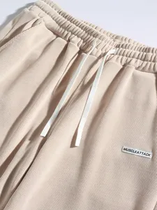 Detail of beige corduroy men's trousers with elastic drawstring waistband and brand patch
