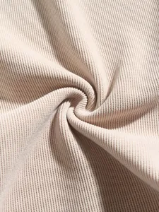 Macro shot of beige corduroy fabric texture showing soft ribbed pattern details.