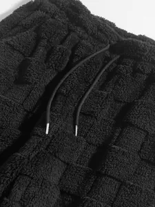 Close-up of black checkerboard textured fleece trousers with adjustable drawstring detail.