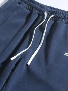 Close-up detail of navy blue corduroy pants featuring elastic waistband and white drawstring