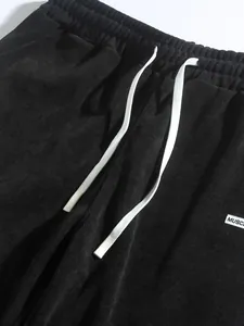 Close-up view showing the black corduroy fabric texture and white drawstring of casual pants
