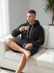 Heren zwarte koraalvlies hoodie en korte broek set getoond in een gezellige woonkamer