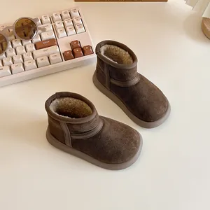 Brown plush-lined children's snow boots for winter warmth, displayed on a beige desk
