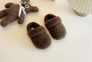 Nahaufnahme von braunen flauschigen Kinderschlappen mit einem Teddybären auf hellem Grund