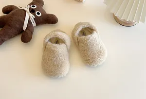 Nahaufnahme der weichen, cremefarbenen Kinder-Fleecepantoffeln mit Teddy-Textur