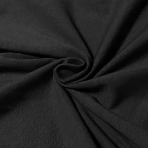 Macro detail of soft black cotton knit fabric showing fine texture and natural folds