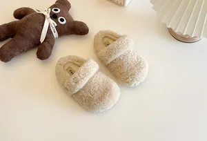 Vista dettagliata di comode pantofole beige in shearling per bambini su fondo bianco.