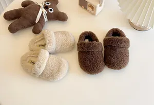Detailansicht der weichen Sherpa-Textur von braunen und cremefarbenen Kinderslippern
