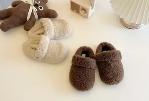 Primer plano de cómodos zuecos de forro polar para niños en beige y marrón para invierno