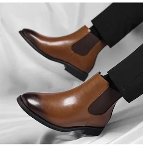 Detail view of brown leather Chelsea boots with side elastic band and sleek finish.