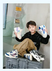 Garçon asiatique élégant présentant diverses baskets montantes pour enfants en couleurs