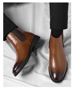 Detailed macro view of men's brown burnished leather Chelsea boots with elegant stitching