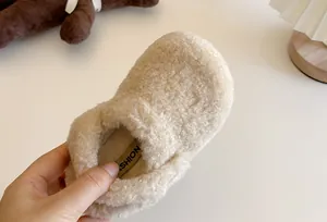 Dettaglio di ciabatte pelose color crema per bambini con texture morbida e calda
