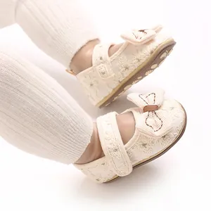 Nahaufnahme von cremefarbenen Baby-Prinzessinenschuhen mit Schleife und Spitzendetails