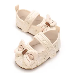 Detaillierte Ansicht cremefarbener Babyschuhe mit floraler Stickerei und Schleife.