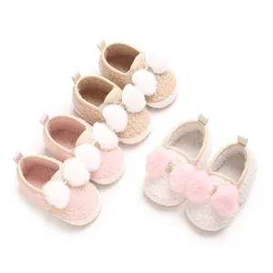 Detailed view of cute baby girl fleece crib shoes with soft soles and colorful pom-poms