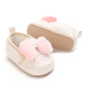 Close-up of cute pink plush bow and non-slip sole on white baby girl walking shoes.