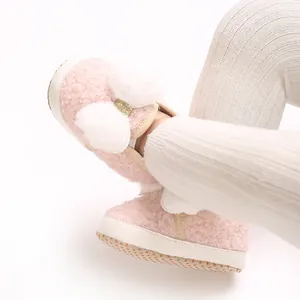 Macro view of pink fuzzy baby girl shoes with white pompoms and gold bow decoration