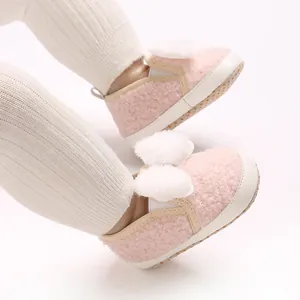 Macro view of pink fuzzy baby girl shoes featuring soft soles and white pom-poms