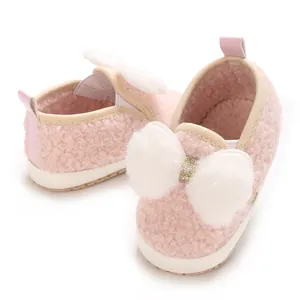Detailed view of cute pink fuzzy baby girl crib shoes with white faux fur bow decoration