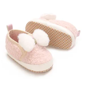 Detailed view of pink fuzzy baby crib shoes with soft non-slip sole and white plush bow