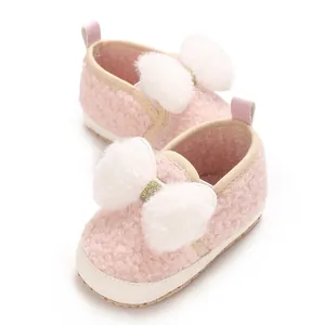 Close-up of cute pink fleece baby girl crib shoes featuring fluffy white fur bows