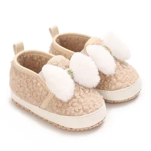Detailed close-up view of beige fleece baby crib shoes with fluffy white faux fur bows