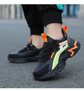 Primer plano de zapatillas deportivas infantiles en negro y naranja en un pie