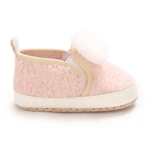 Detailed side view of a soft pink baby girl crib shoe with a plush white pom-pom
