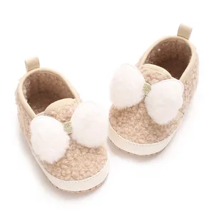 Soft beige sherpa baby girl crib shoes with cute white fluffy pom-pom bow detail