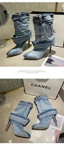 Detail view of denim stiletto ankle boots with folded pant leg design and pointed toe.