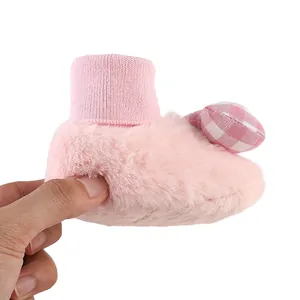 Close-up detail of soft pink fuzzy baby winter bootie with cute checkered bow ornament